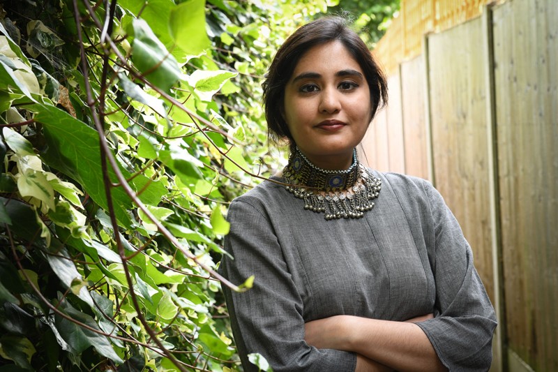 Lalah Ruh poses for a portrait next to a green ivy